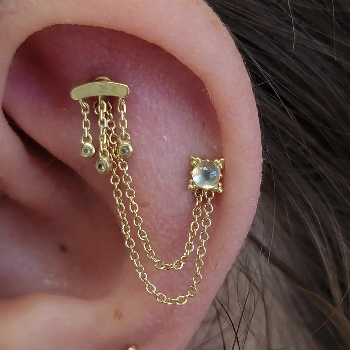 Flat and Helix piercings adorned with a chain all in 18k and 14k yellow gold